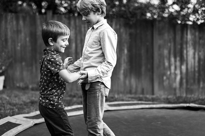 Mom, dad and their 2 boys playing in their backyard.