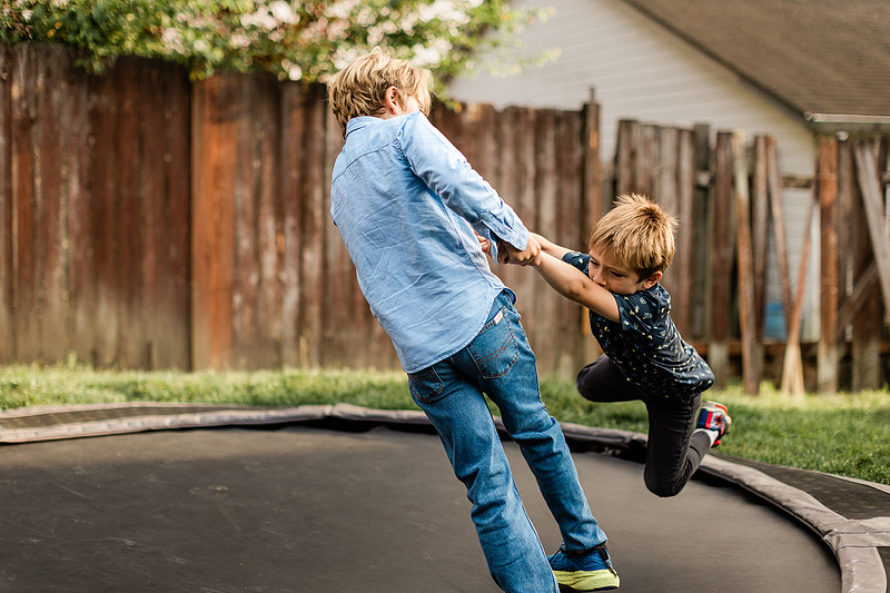 Mom, dad and their 2 boys playing in their backyard.