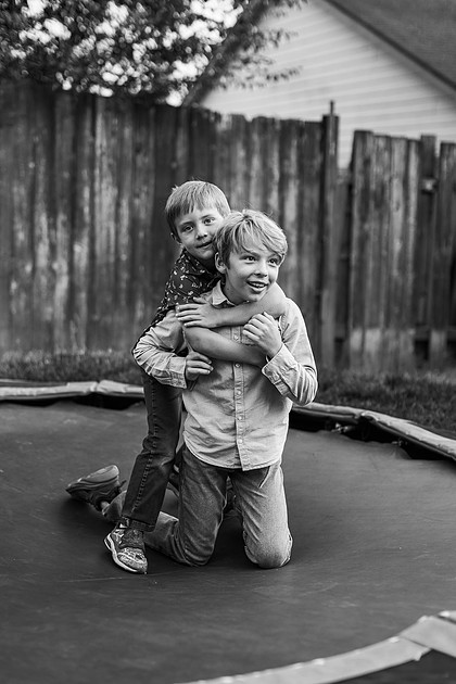Mom, dad and their 2 boys playing in their backyard.