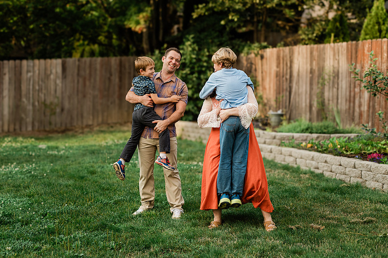 Mom, dad and their 2 boys playing in their backyard.