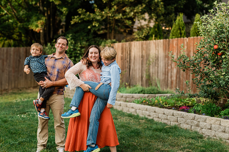 Mom, dad and their 2 boys playing in their backyard.
