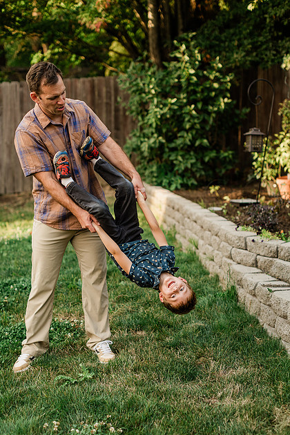 Mom, dad and their 2 boys playing in their backyard.