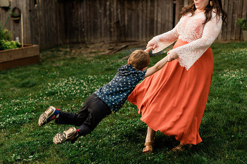 Mom, dad and their 2 boys playing in their backyard.