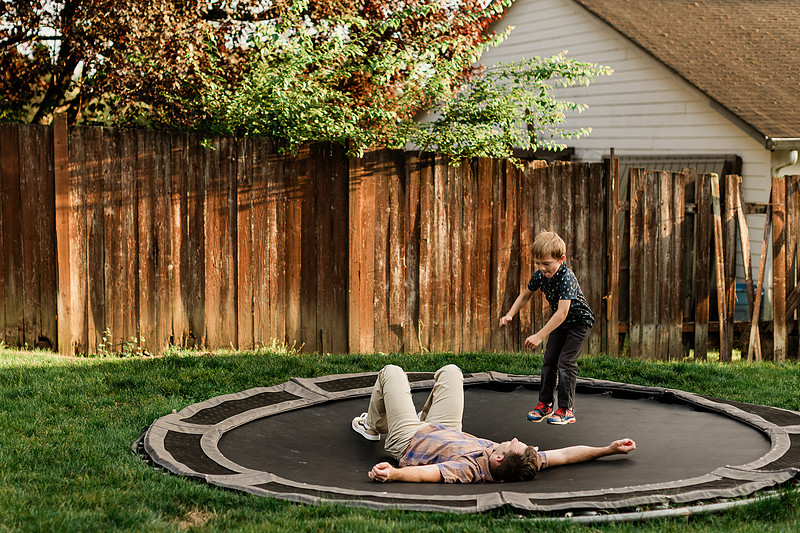 Mom, dad and their 2 boys playing in their backyard.