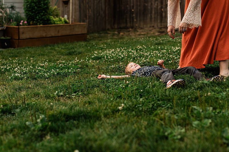 Mom, dad and their 2 boys playing in their backyard.