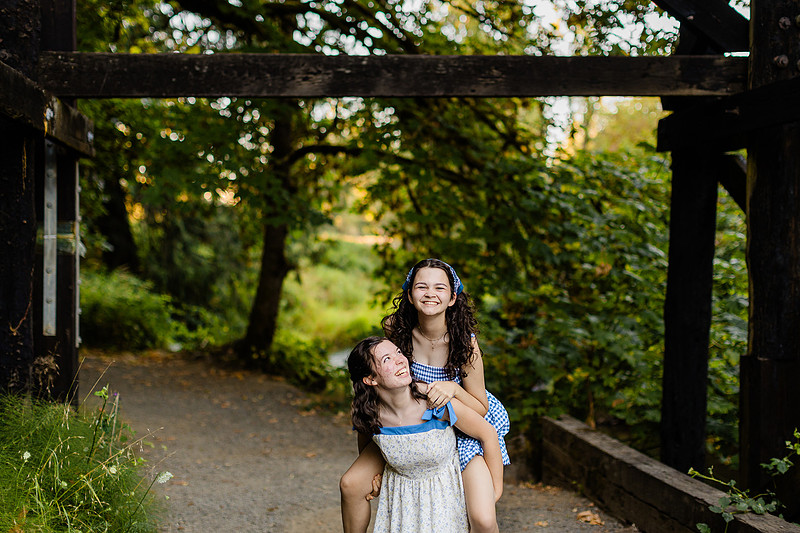 2 female friends playing in a field with trees