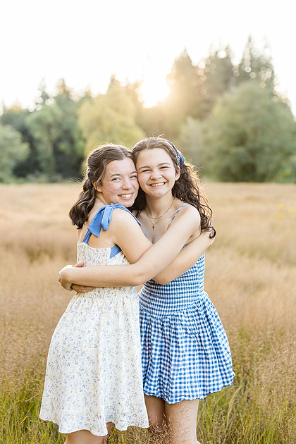 2 female friends playing in a field with trees