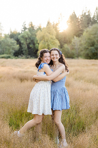 2 female friends playing in a field with trees