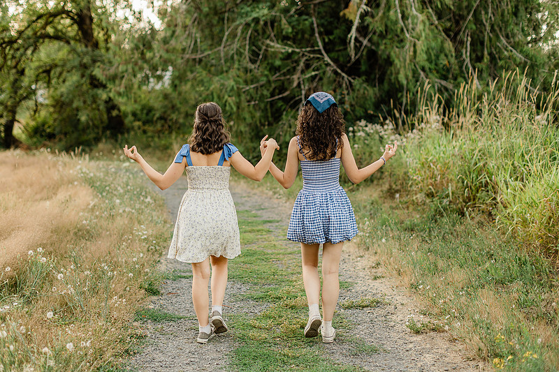 2 female friends playing in a field with trees