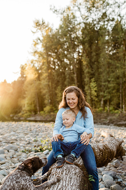 a boy, his mom and their dog playing by the river