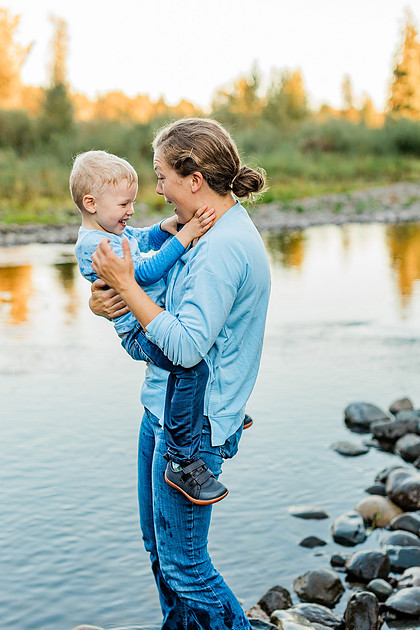 a boy, his mom and their dog playing by the river