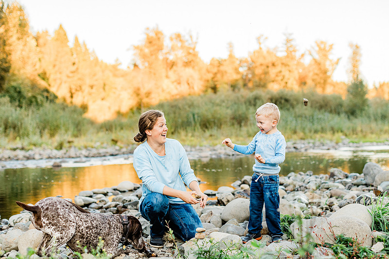 a boy, his mom and their dog playing by the river