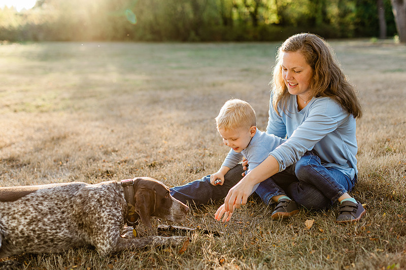 a boy, his mom and their dog playing by the river