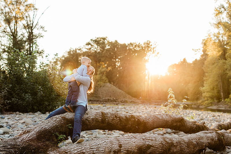 a boy, his mom and their dog playing by the river
