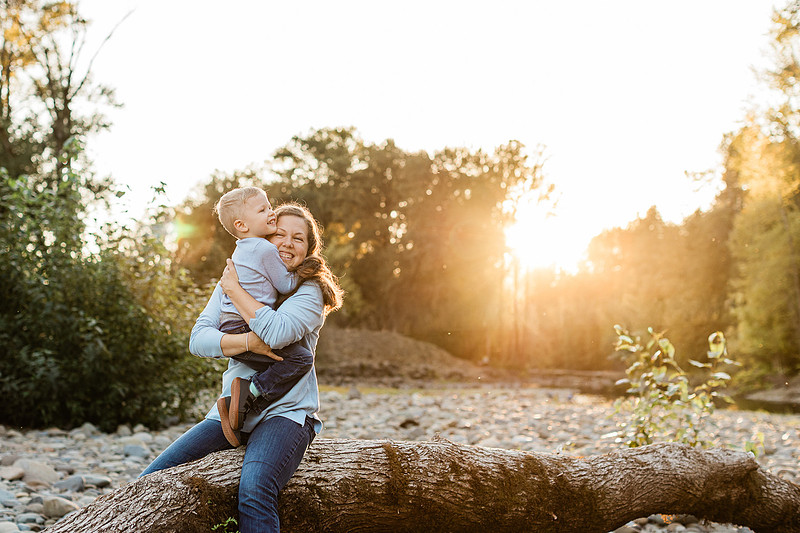 a boy, his mom and their dog playing by the river