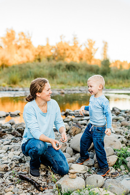 a boy, his mom and their dog playing by the river