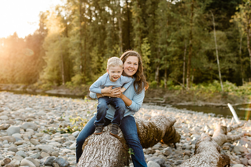 a boy, his mom and their dog playing by the river
