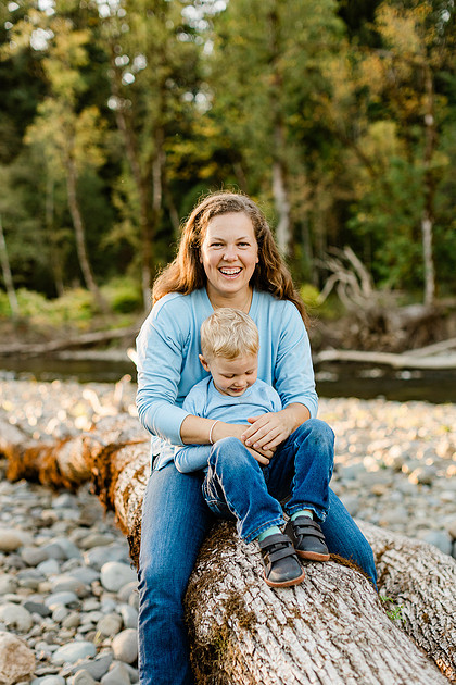a boy, his mom and their dog playing by the river