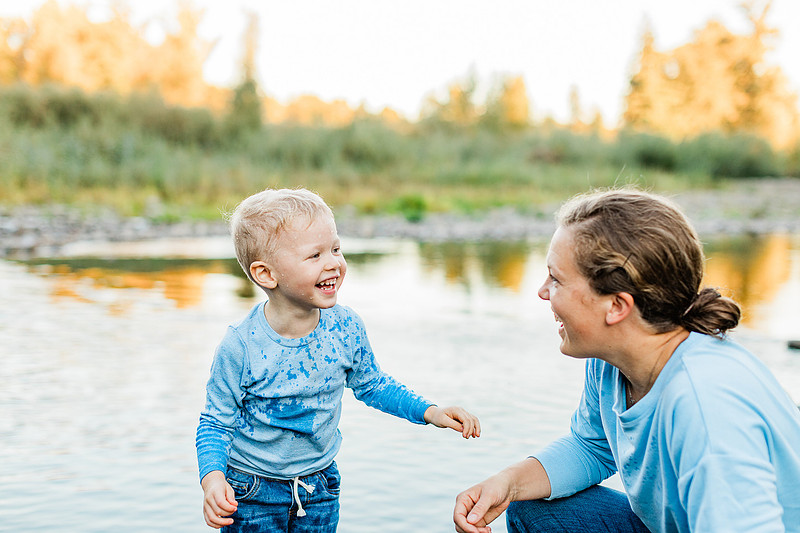 a boy, his mom and their dog playing by the river