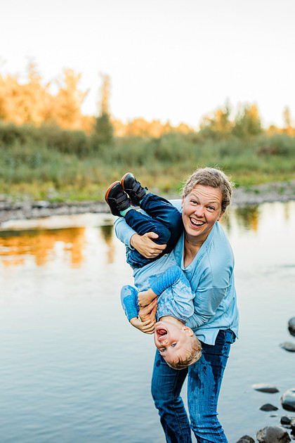 a boy, his mom and their dog playing by the river
