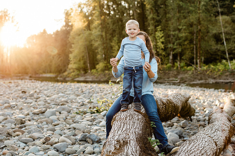 a boy, his mom and their dog playing by the river