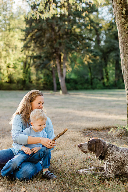 a boy, his mom and their dog playing by the river