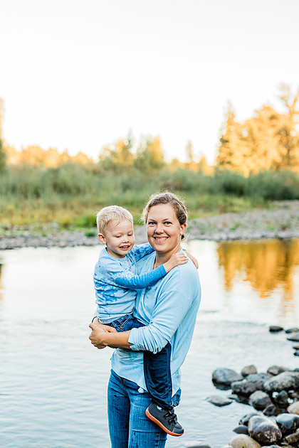a boy, his mom and their dog playing by the river