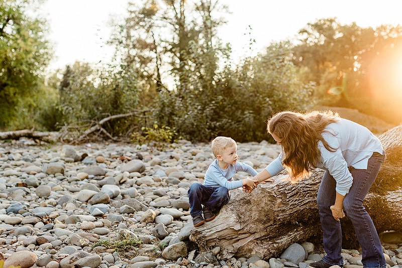 a boy, his mom and their dog playing by the river