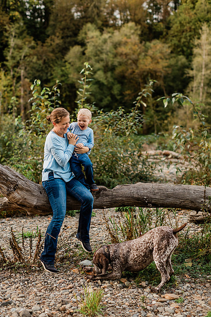 a boy, his mom and their dog playing by the river