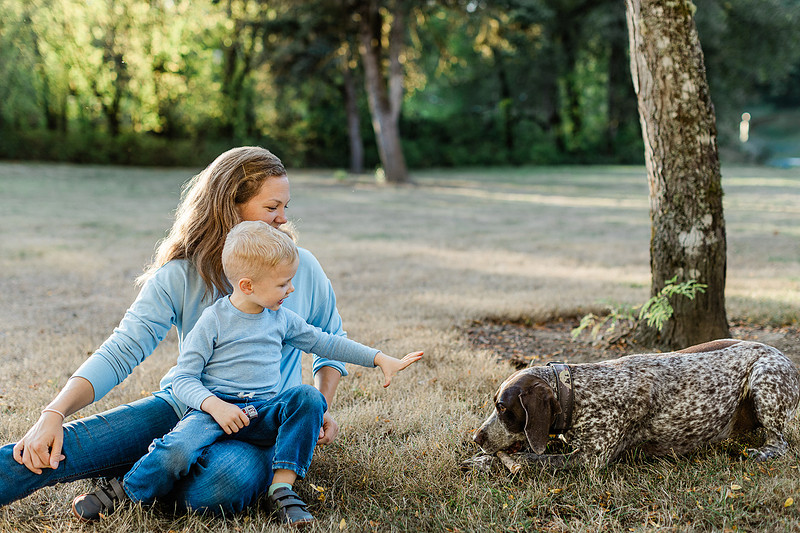 a boy, his mom and their dog playing by the river