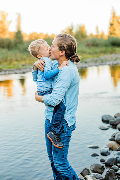 a boy, his mom and their dog playing by the river