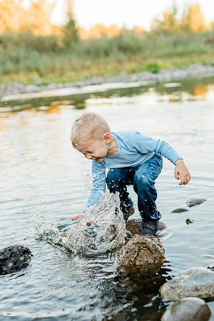 a boy, his mom and their dog playing by the river