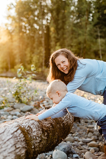 a boy, his mom and their dog playing by the river