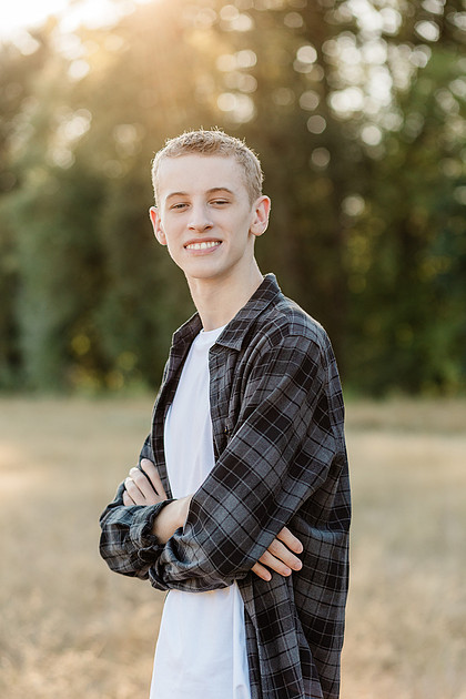 Senior boy in a field with large trees