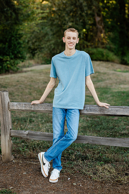 Senior boy by a fence in front of trees in Vancouver, WA