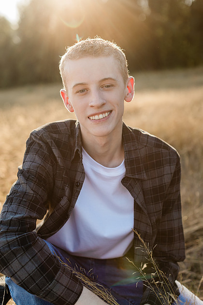 Senior boy in a field with large trees