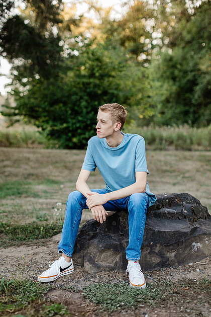 Senior boy by a fence in front of trees in Vancouver, WA