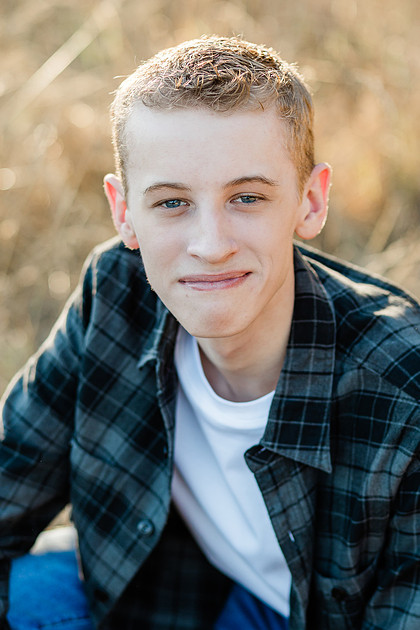 Senior boy in a field with large trees