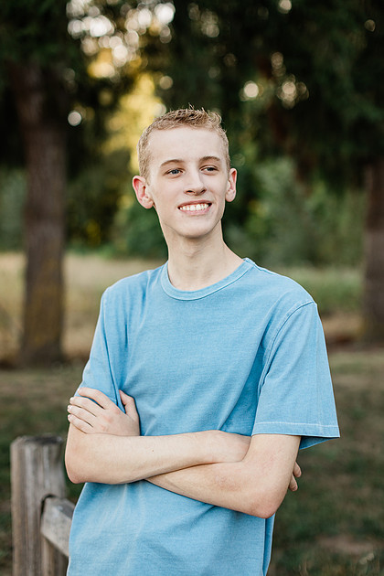 Senior boy by a fence in front of trees in Vancouver, WA
