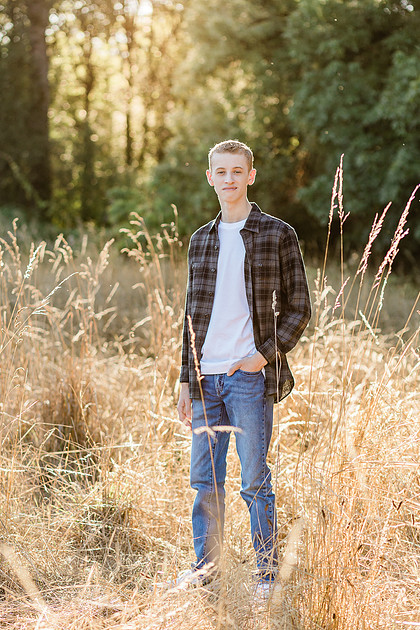 Senior boy in a field with large trees