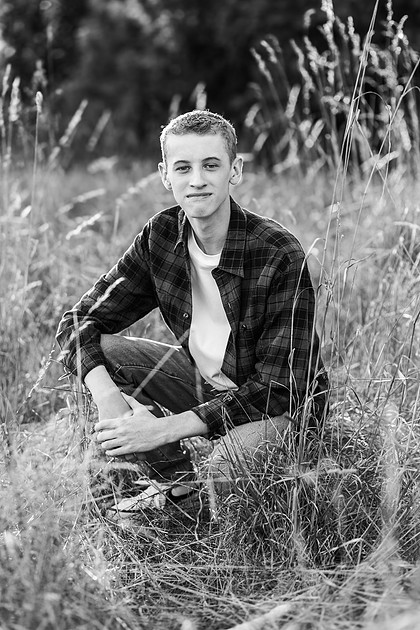 Senior boy in a field with large trees