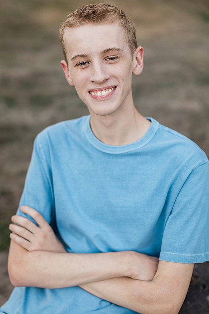 Senior boy by a fence in front of trees in Vancouver, WA